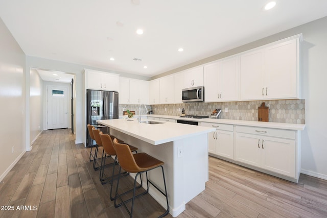 29339 N 135th Dr, Peoria, AZ 85383 - kitchen with appliances with stainless steel finishes, a sink, decorative backsplash, light wood finished floors, and recessed lighting