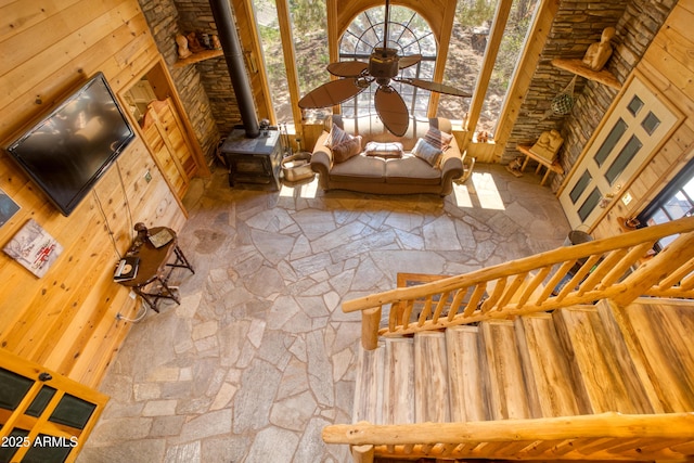 8455 Ridge Dr, Show Low, AZ 85901 - unfurnished living room featuring ceiling fan, a towering ceiling, wood walls, and a wood stove