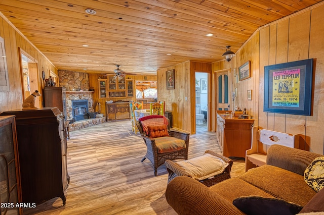 8455 Ridge Dr, Show Low, AZ 85901 - living room with a wood stove, wooden walls, a ceiling fan, wood ceiling, and light wood-style floors