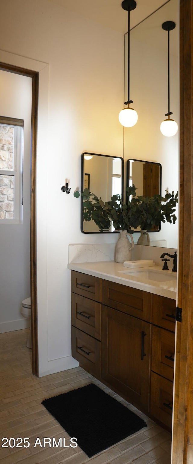 bathroom with toilet, baseboards, vanity, and wood finished floors