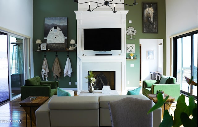 living area featuring a fireplace, a high ceiling, plenty of natural light, and wood finished floors