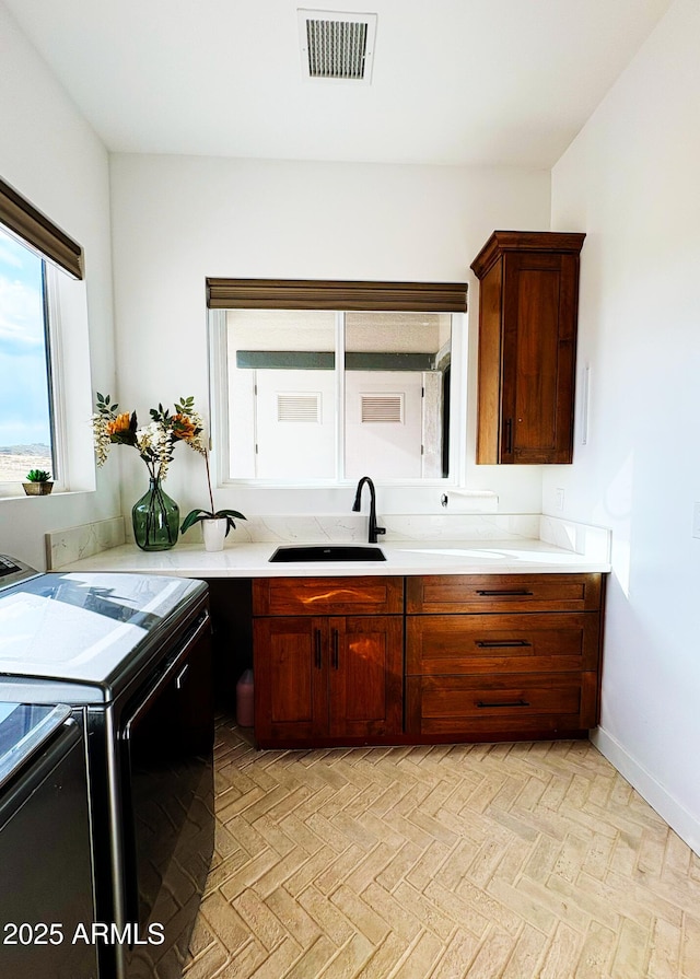 kitchen with baseboards, stove, visible vents, a sink, and light countertops
