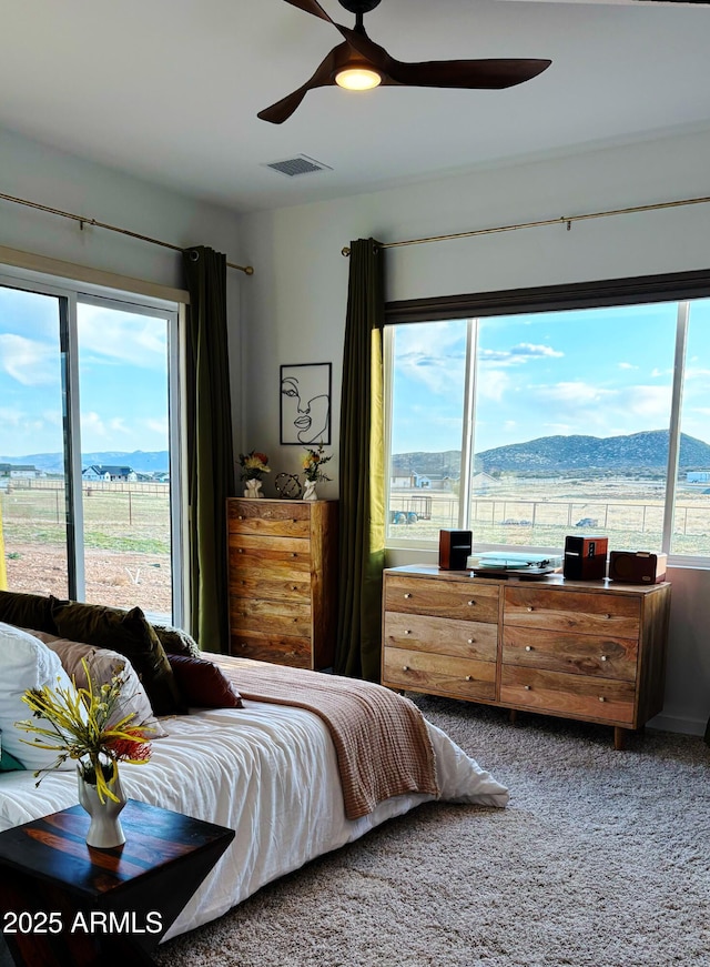 bedroom with ceiling fan, a mountain view, carpet, and visible vents