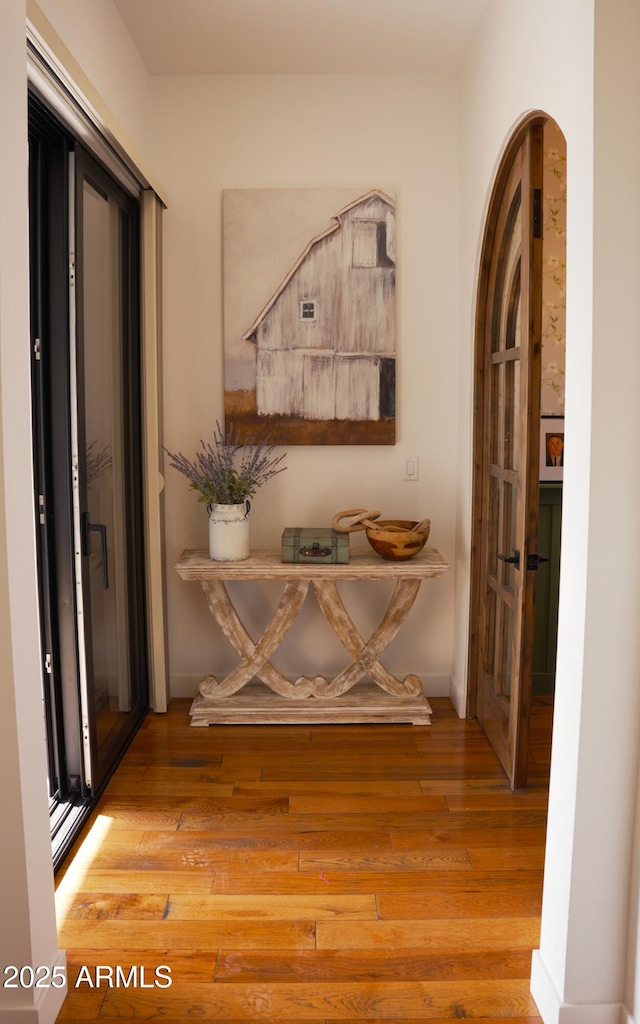 hall with french doors, baseboards, and wood-type flooring