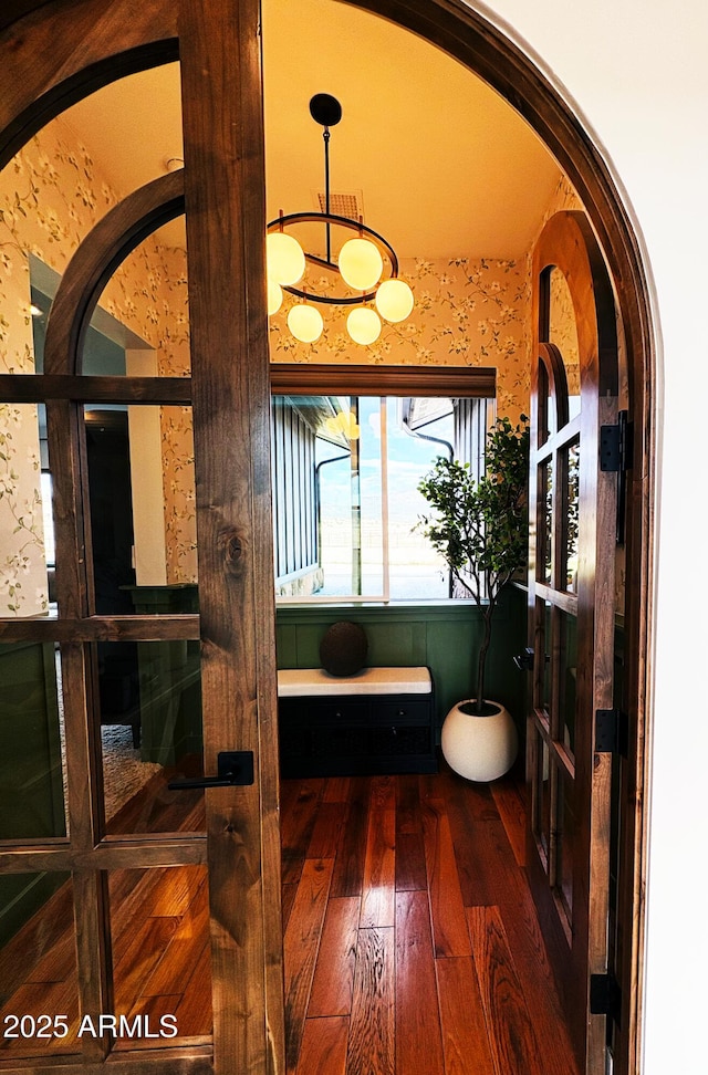 interior space with wallpapered walls, wood-type flooring, and a notable chandelier