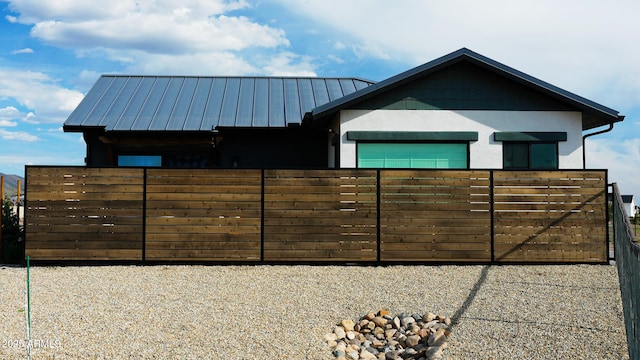 exterior space featuring an attached garage, stucco siding, fence, metal roof, and a standing seam roof