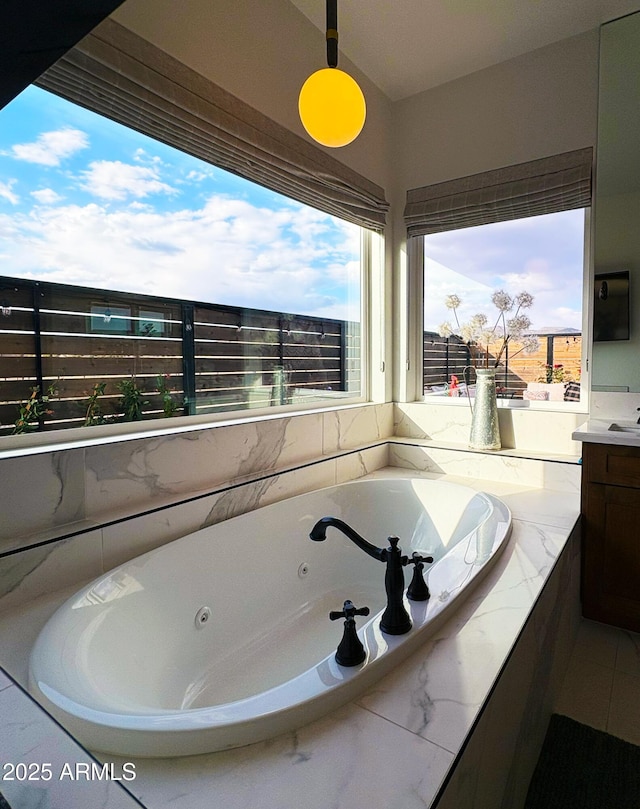 bathroom with a wealth of natural light, tile patterned flooring, a jetted tub, and vanity