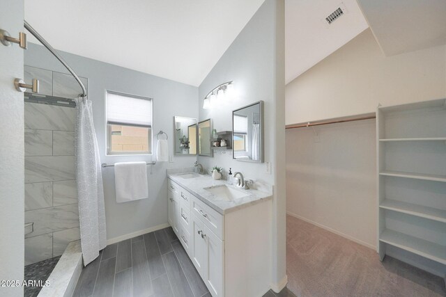 2627 E Gary Way, Phoenix, AZ 85042 - bathroom with a tile shower, baseboards, double vanity, lofted ceiling, and a spacious closet
