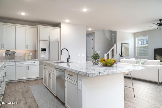 kitchen featuring white cabinets, a kitchen island with sink, open floor plan, and a sink
