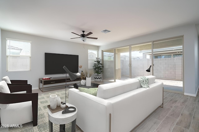 living area with a wealth of natural light, light wood-type flooring, visible vents, and baseboards