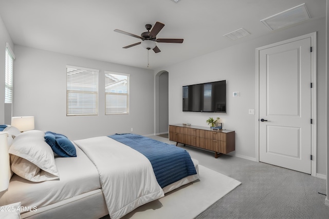 bedroom featuring light carpet, baseboards, multiple windows, and arched walkways