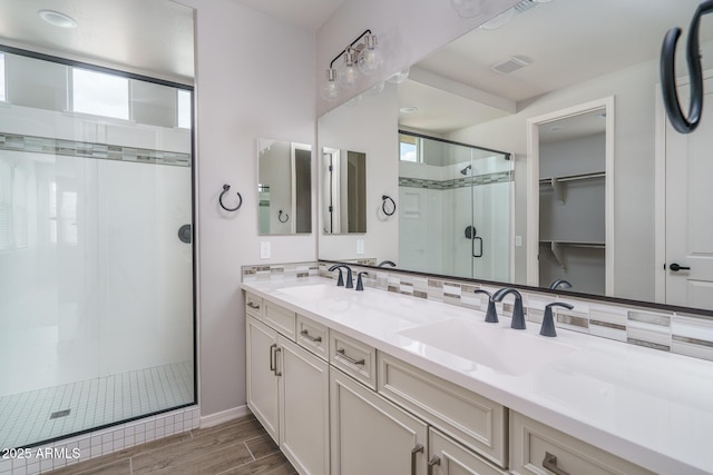 full bath featuring a stall shower, a walk in closet, a sink, and decorative backsplash