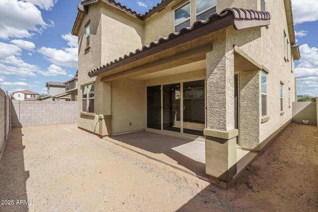 rear view of house featuring a patio area, a fenced backyard, a tile roof, and stucco siding