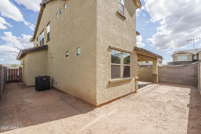 view of property exterior with central AC unit, a patio area, fence, and stucco siding