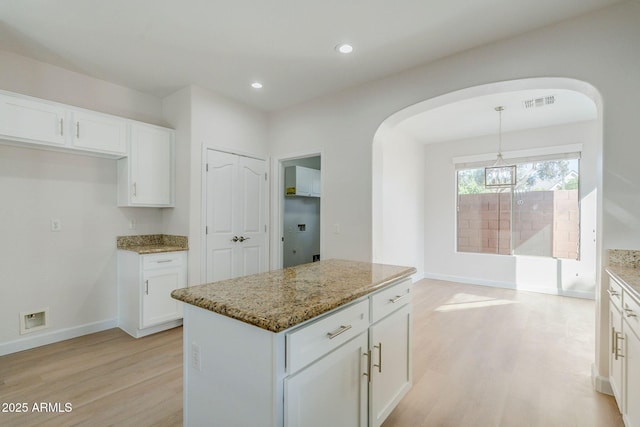 4389 E Muirfield St, Gilbert, AZ 85298 - kitchen with white cabinetry, light wood-type flooring, arched walkways, and light stone countertops