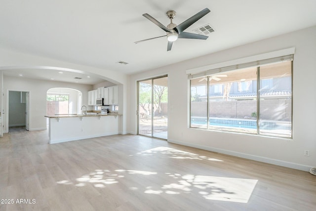4389 E Muirfield St, Gilbert, AZ 85298 - unfurnished living room with light wood-style flooring, visible vents, baseboards, and arched walkways