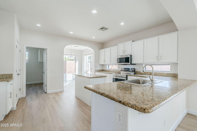 4389 E Muirfield St, Gilbert, AZ 85298 - kitchen featuring arched walkways, light wood-type flooring, a center island, appliances with stainless steel finishes, and a sink