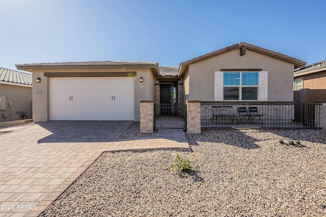 ranch-style house featuring a tiled roof, stucco siding, an attached garage, and decorative driveway