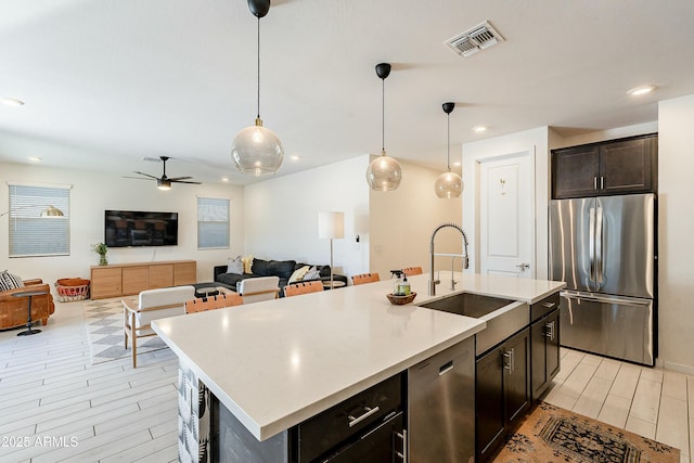 kitchen with visible vents, wood finish floors, hanging light fixtures, stainless steel appliances, and a sink