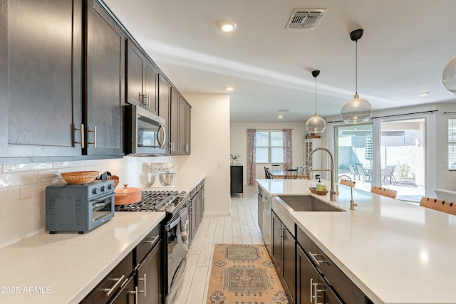 kitchen with visible vents, a sink, black gas range, stainless steel microwave, and backsplash