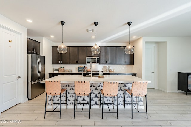 kitchen featuring a kitchen bar, backsplash, appliances with stainless steel finishes, and light countertops