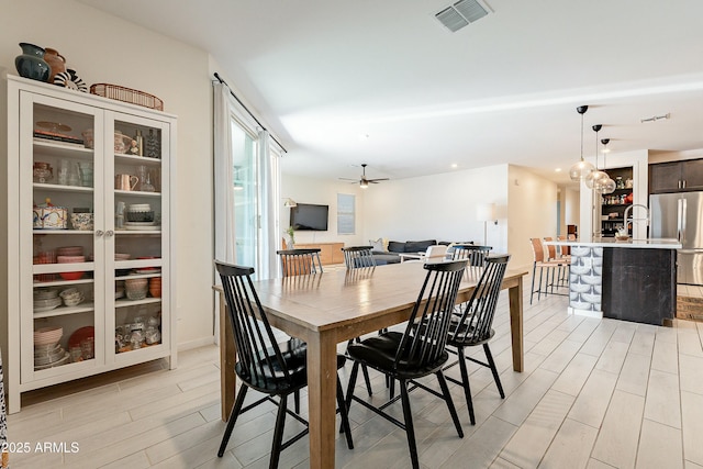 dining space with a ceiling fan, visible vents, and light wood finished floors