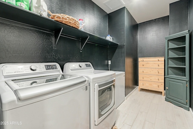 laundry area with laundry area, light wood-style flooring, visible vents, and washing machine and clothes dryer