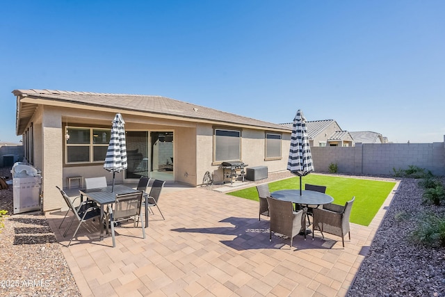 view of patio with outdoor dining space, area for grilling, and a fenced backyard