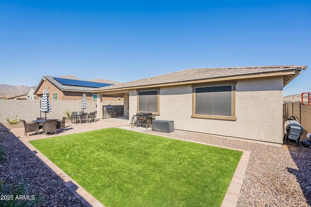 back of house with a yard, stucco siding, a patio, and a fenced backyard