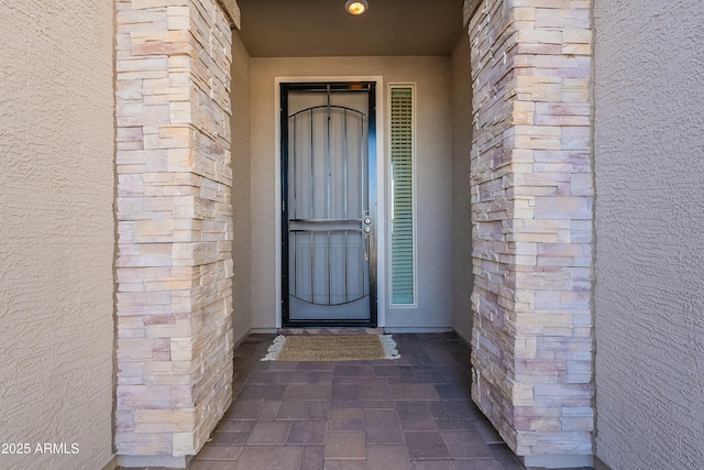 doorway to property with brick siding and stucco siding