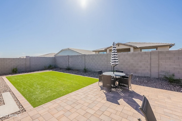 view of yard featuring a fenced backyard, outdoor dining area, and a patio