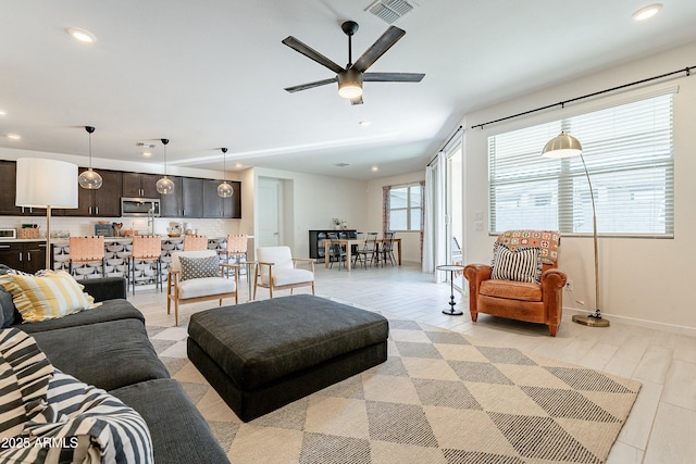 living area with a ceiling fan, visible vents, light wood finished floors, baseboards, and recessed lighting