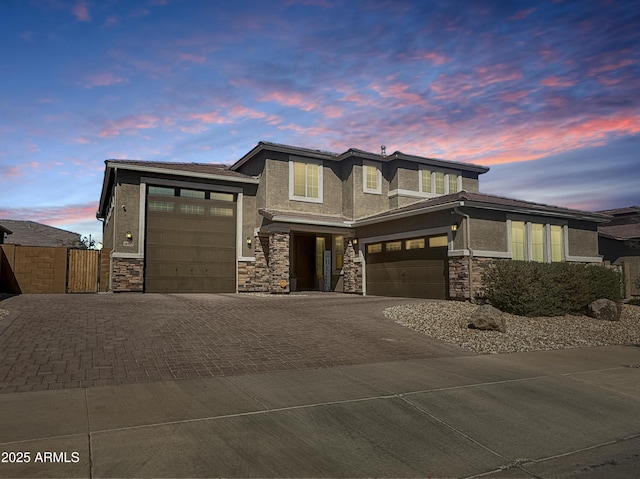 prairie-style house featuring decorative driveway, stone siding, and stucco siding