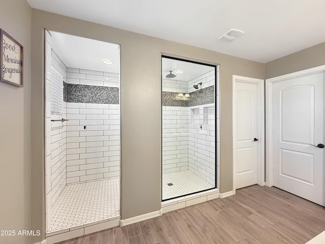 bathroom with visible vents, a stall shower, baseboards, and wood finished floors