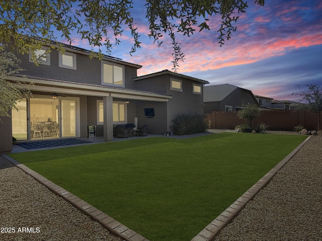 rear view of property with a patio area, a yard, fence, and stucco siding