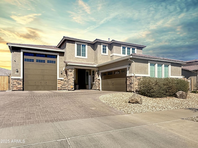 prairie-style home featuring stone siding, stucco siding, driveway, and a garage