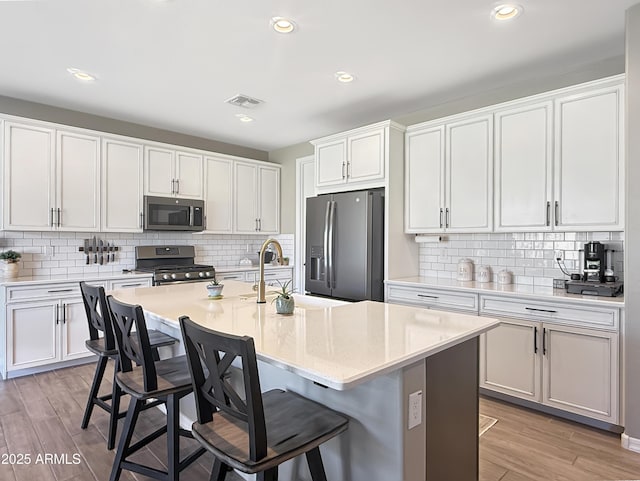 kitchen with light wood-type flooring, a kitchen bar, appliances with stainless steel finishes, and light countertops