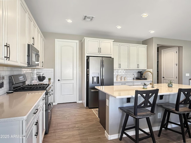 kitchen featuring visible vents, a kitchen breakfast bar, stainless steel appliances, and a sink