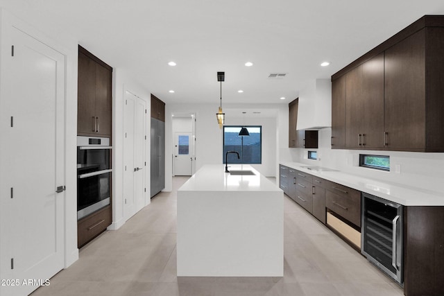 kitchen featuring sink, hanging light fixtures, double oven, black electric stovetop, and beverage cooler