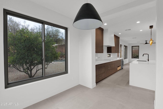 kitchen featuring black electric stovetop, wall chimney exhaust hood, and sink