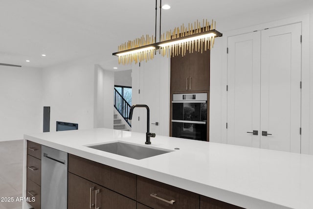 kitchen featuring pendant lighting, appliances with stainless steel finishes, sink, and dark brown cabinets