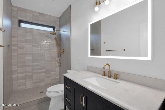 bathroom featuring vanity, toilet, and a tile shower