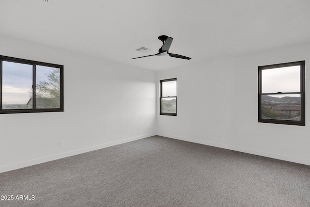 carpeted empty room with ceiling fan and plenty of natural light