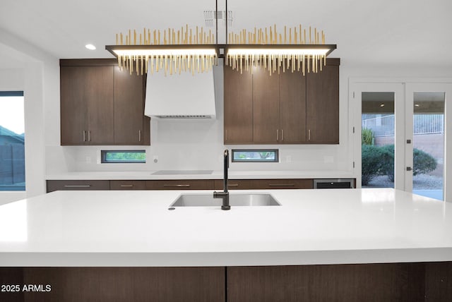 kitchen with decorative light fixtures, sink, a kitchen island with sink, dark brown cabinetry, and black electric cooktop