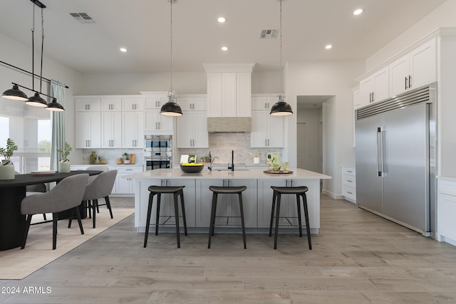 kitchen featuring a large island with sink, white cabinets, and stainless steel appliances