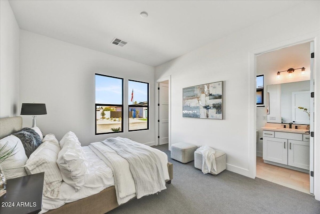 carpeted bedroom with sink and ensuite bathroom