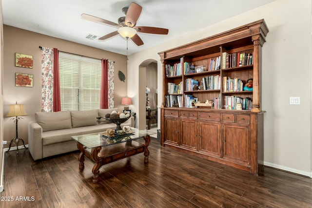living room with visible vents, arched walkways, ceiling fan, and dark wood-style flooring