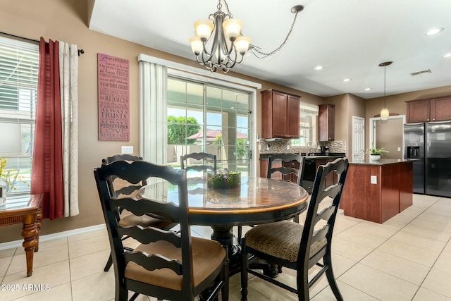 dining room with light tile patterned floors, visible vents, a wealth of natural light, and a chandelier