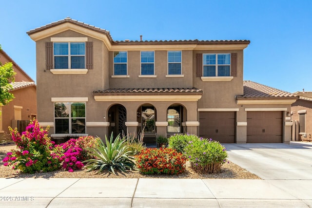 mediterranean / spanish-style house with stucco siding, driveway, and a tile roof