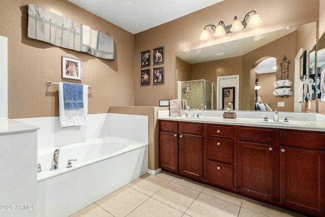 full bath with tile patterned floors, a shower stall, double vanity, a sink, and a garden tub